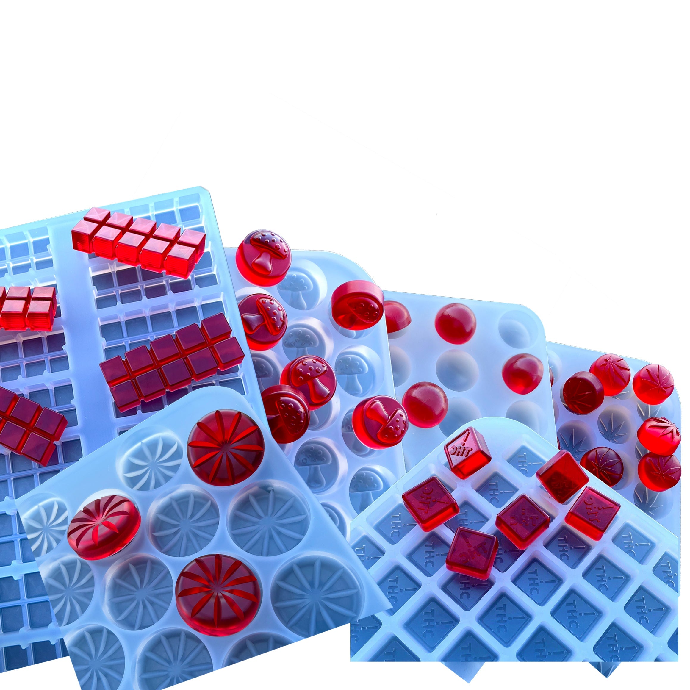 Assorted blue silicone molds filled with solid red candies in various geometric shapes, arranged overlapping on a white background.