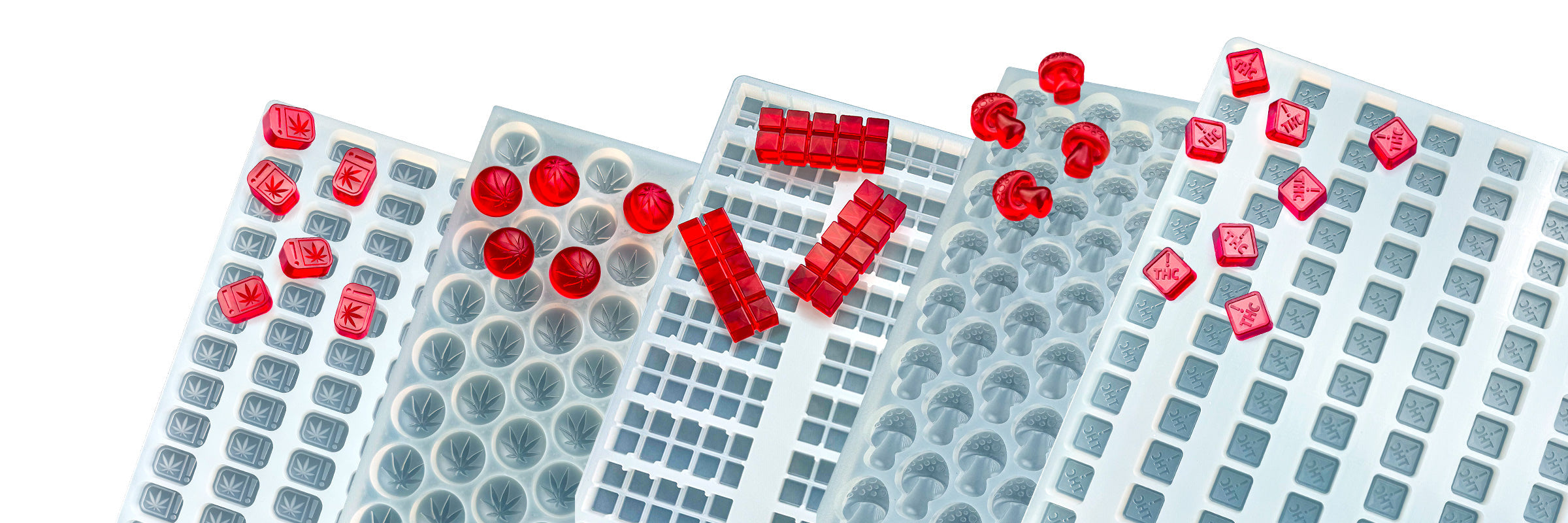 Assorted blue silicone molds filled with solid red candies in various geometric shapes, arranged overlapping on a white background.