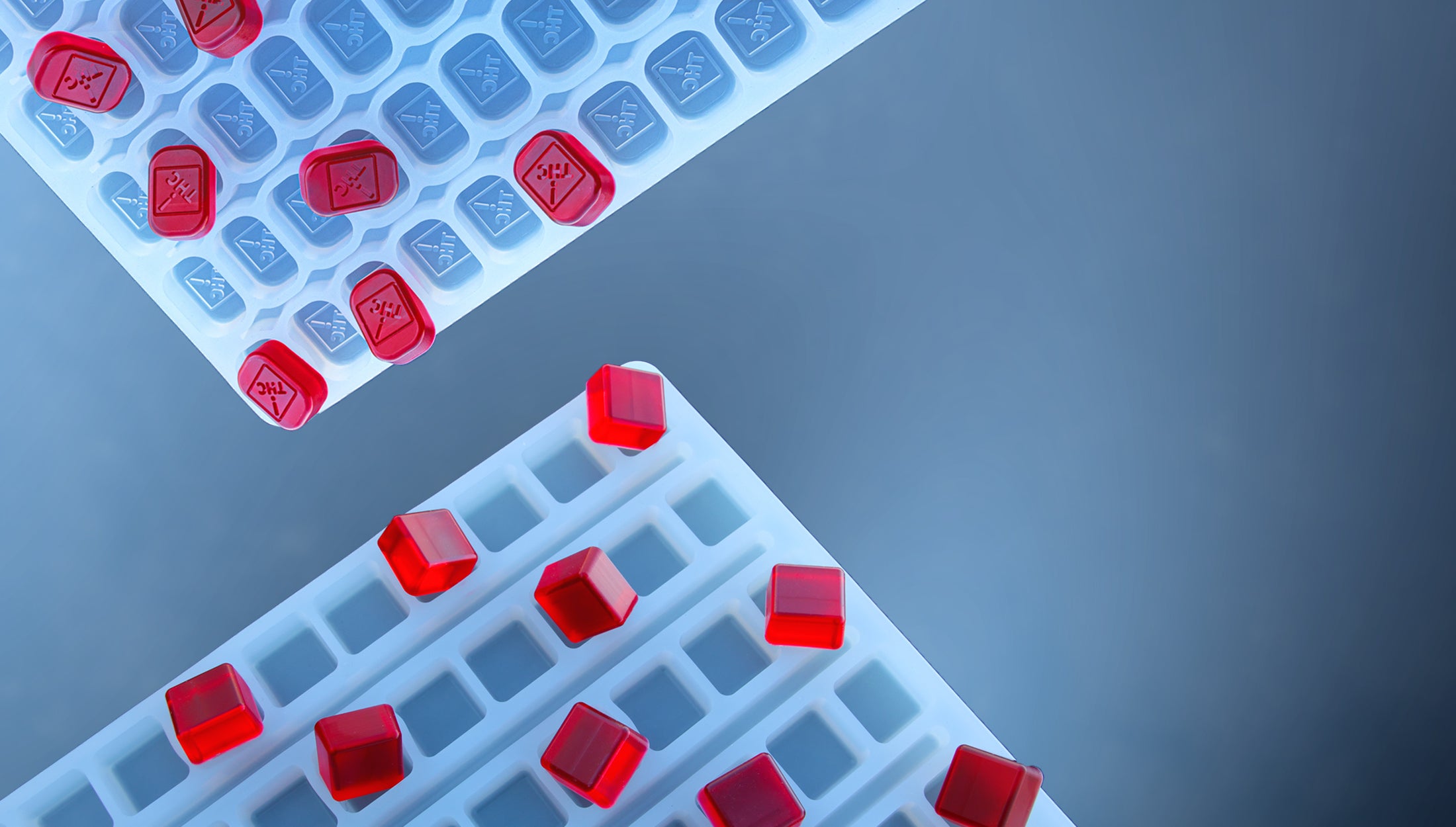 Two white laboratory sample trays with several square red-capped vials, positioned on a blue gradient background.