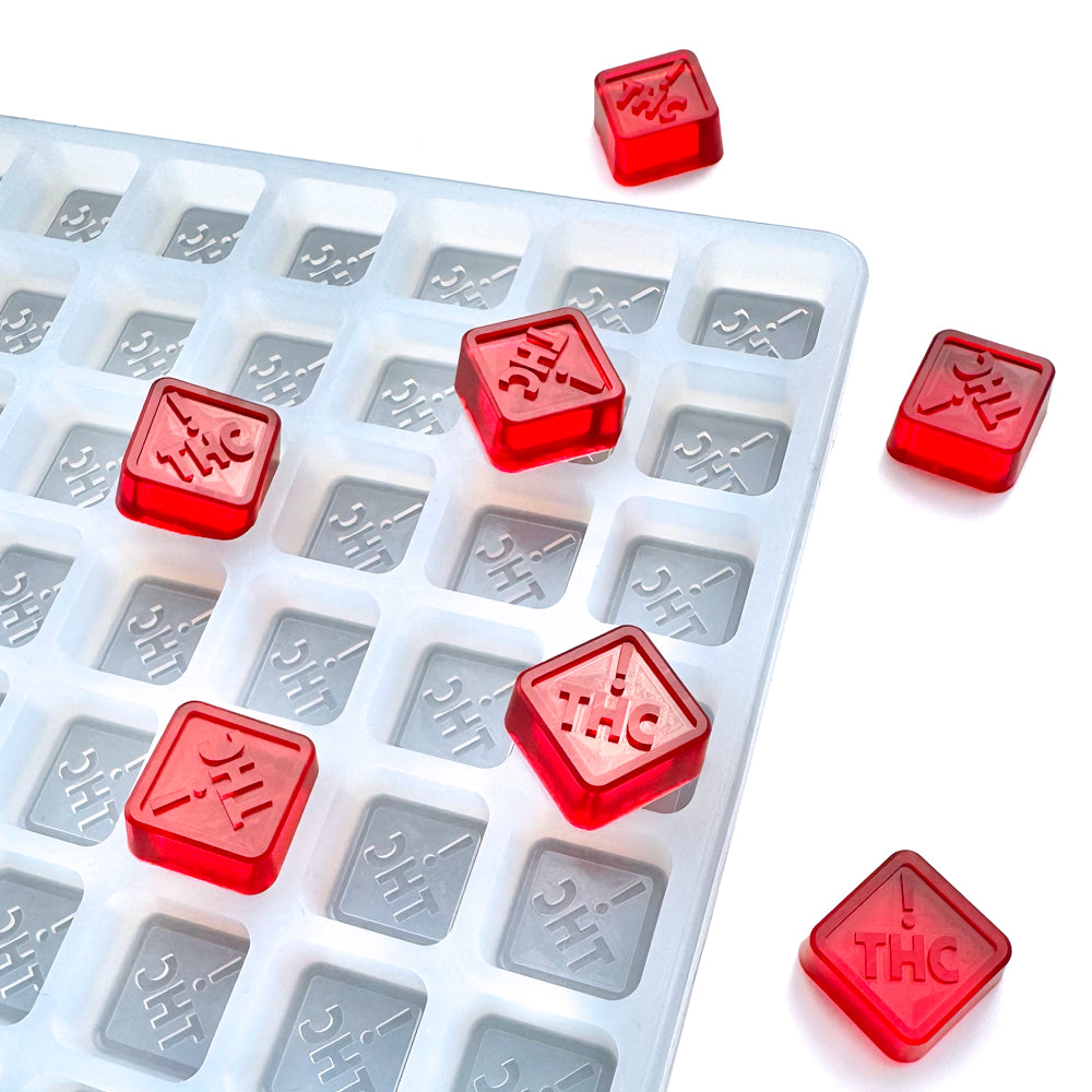 A Vector Molds 2.5 mL Square Gummy Mold - CO, OH, NM & FL THC Logo Mold (Half Sheet, 262 Cavities) displays red THC-labeled gummies in its BPA-free silicone tray on a white surface.