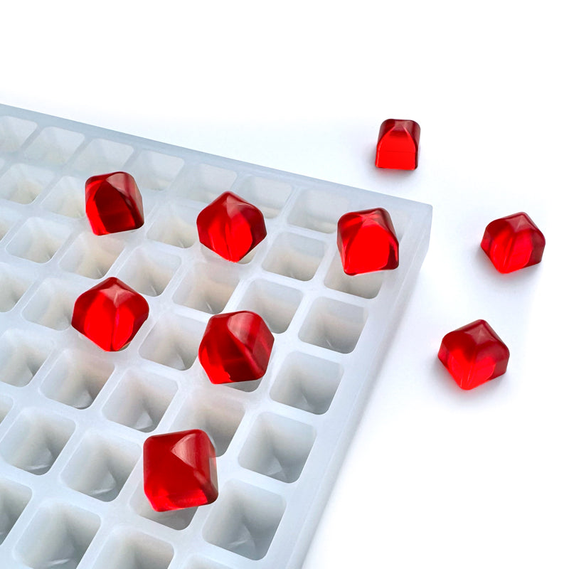 A Vector Molds 2 mL Rounded Top Square Gummy Mold (Sharp Half Sheet, 391 cavities) holds vivid red, gem-like gummies on a white surface, with some gummies inside the tray and others scattered nearby.