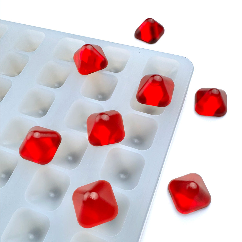 Custom food-grade silicone pyramid gummy mold, 3ml cavities with defined edges and smooth demolding, shown with red gummies, universal depositor compatible.