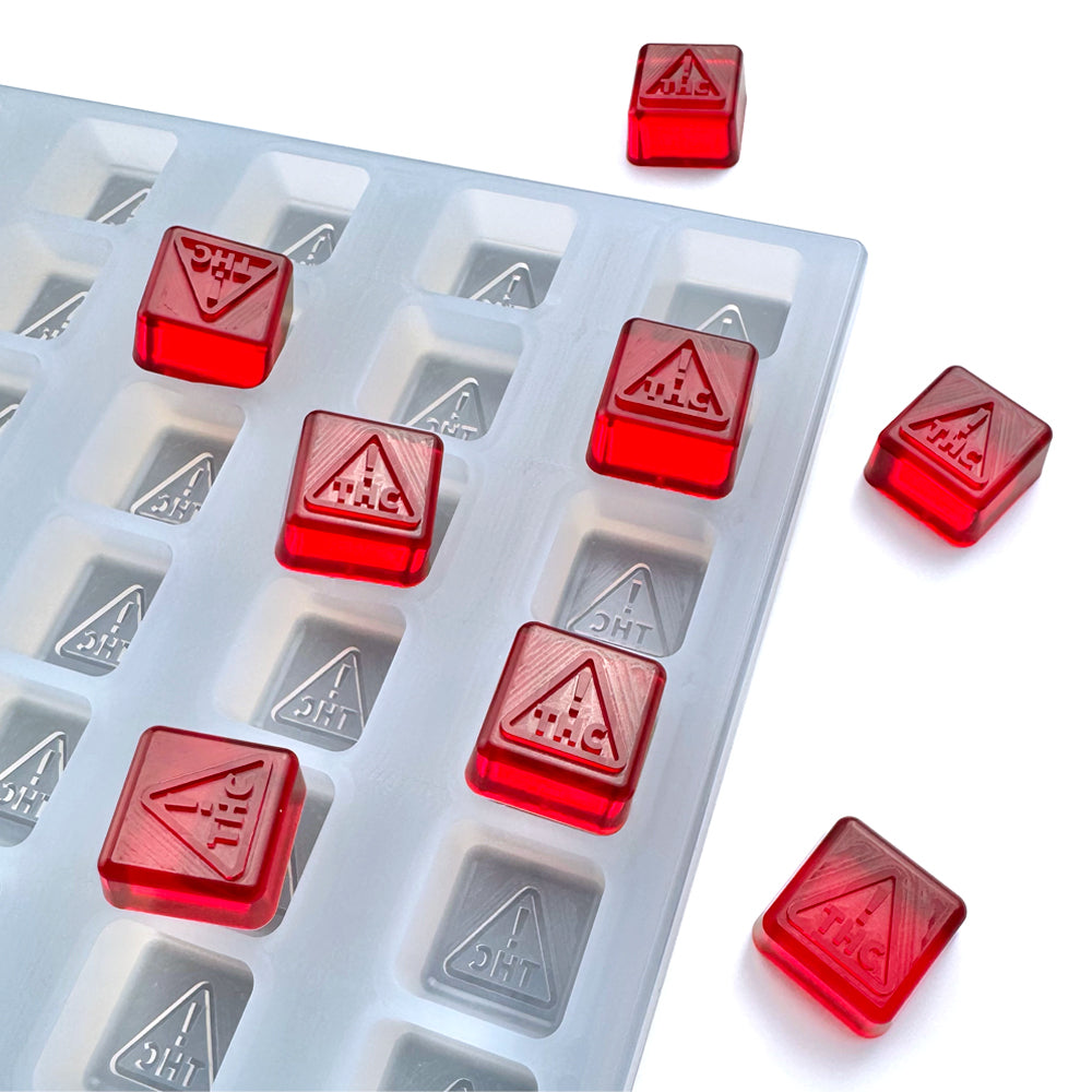 Food-grade custom silicone square gummy mold, 4ml cavities featuring NV and MS-compliant logo design, shown with red gummies, universal depositor compatible.