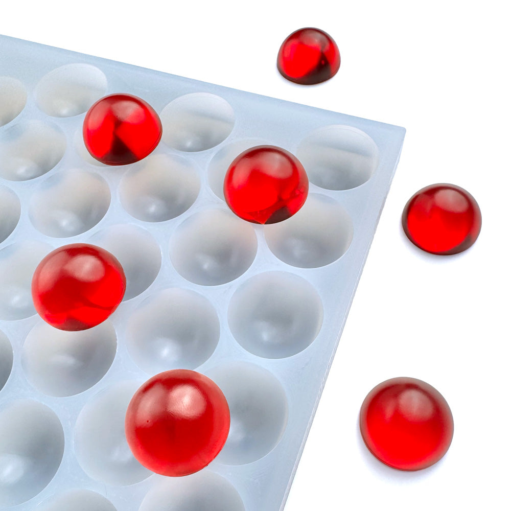The Vector Molds 5 mL Bon Bon Mold - Sharp Half Sheet with 149 cavities is a white silicone tray that holds glossy red spheres, with three displayed outside the professional food-grade mold on a white background.