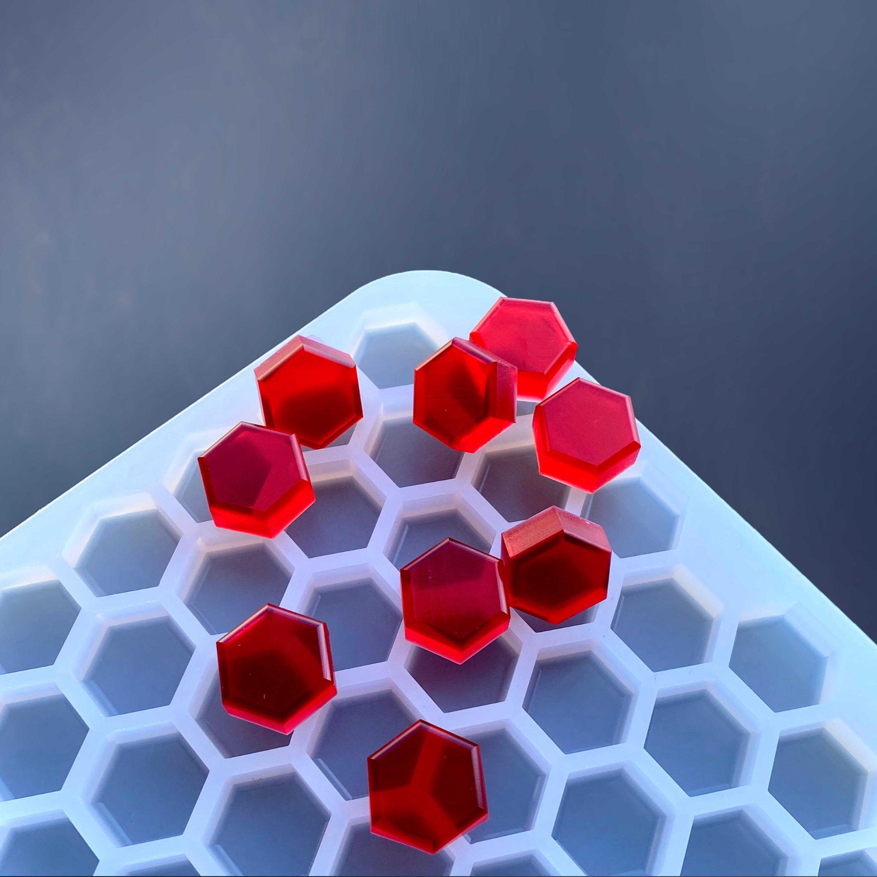 Red hexagonal gummies from the Vector Molds 2 mL Hexagon Gummy Mold (Half Sheet, 331 Cavities) rest on a white honeycomb-patterned tray against a dark blue background.