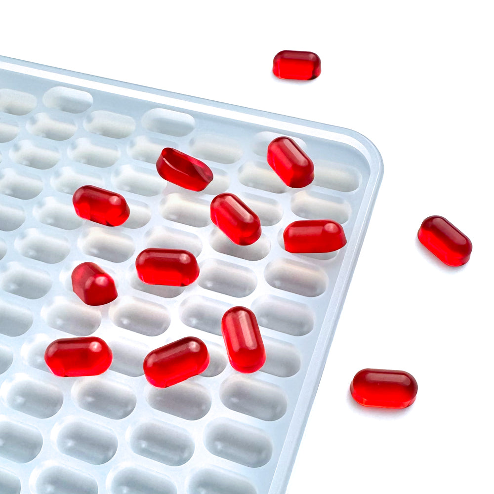  Custom food-grade silicone capsule gummy mold, 0.5ml oval cavities designed for flood-and-scrape pouring, shown with red gummies, ideal for manual production.