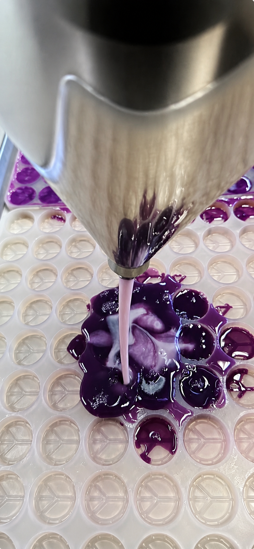 Close-up of industrial gummy depositing process using Vector Molds food-grade platinum silicone molds for commercial gummy manufacturing. Precision depositor machine filling custom silicone molds with supplement-based gummy mixture for nutraceutical, vitamin, protein, candy, and confectionery production. High-performance FDA-compliant silicone gummy molds designed for automated depositing systems, flood-and-scrape production, and high-volume candy manufacturing. Durable easy-release silicone molds engineere
